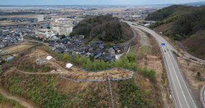 観法寺墳墓群のある丘陵を山側の上空からみたところ。集落を挟んで向こう側には観法寺古墳群があった丘陵もみえます。